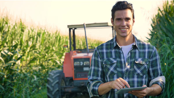 Bauer vor Traktor im Feld mit Tablet
